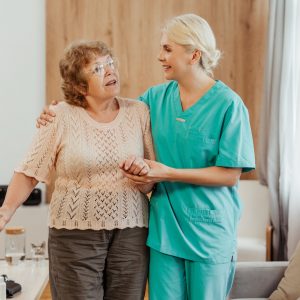 smiling-nurse-assisting-elderly-woman-using-walking-cane-home